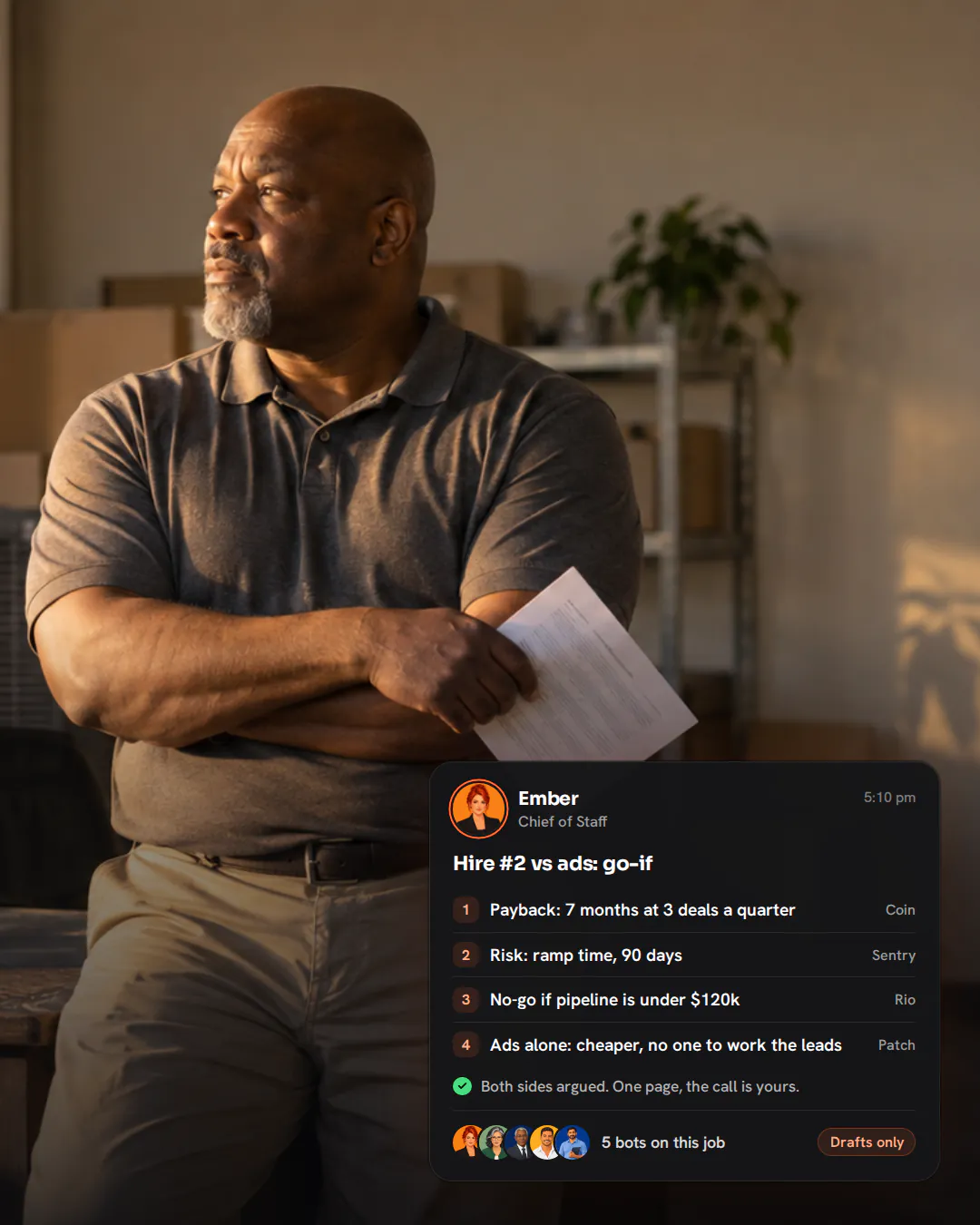 An HVAC business owner leaning on his desk with arms folded, holding a page and looking out of a window at golden hour.