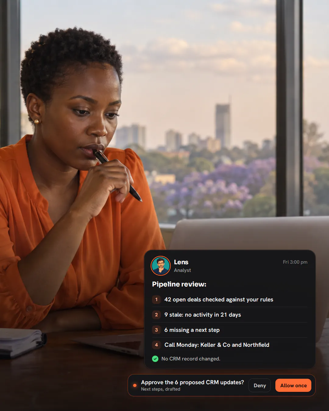 A sales lead in an orange blouse leaning over a laptop in a glass meeting room on a Friday afternoon.