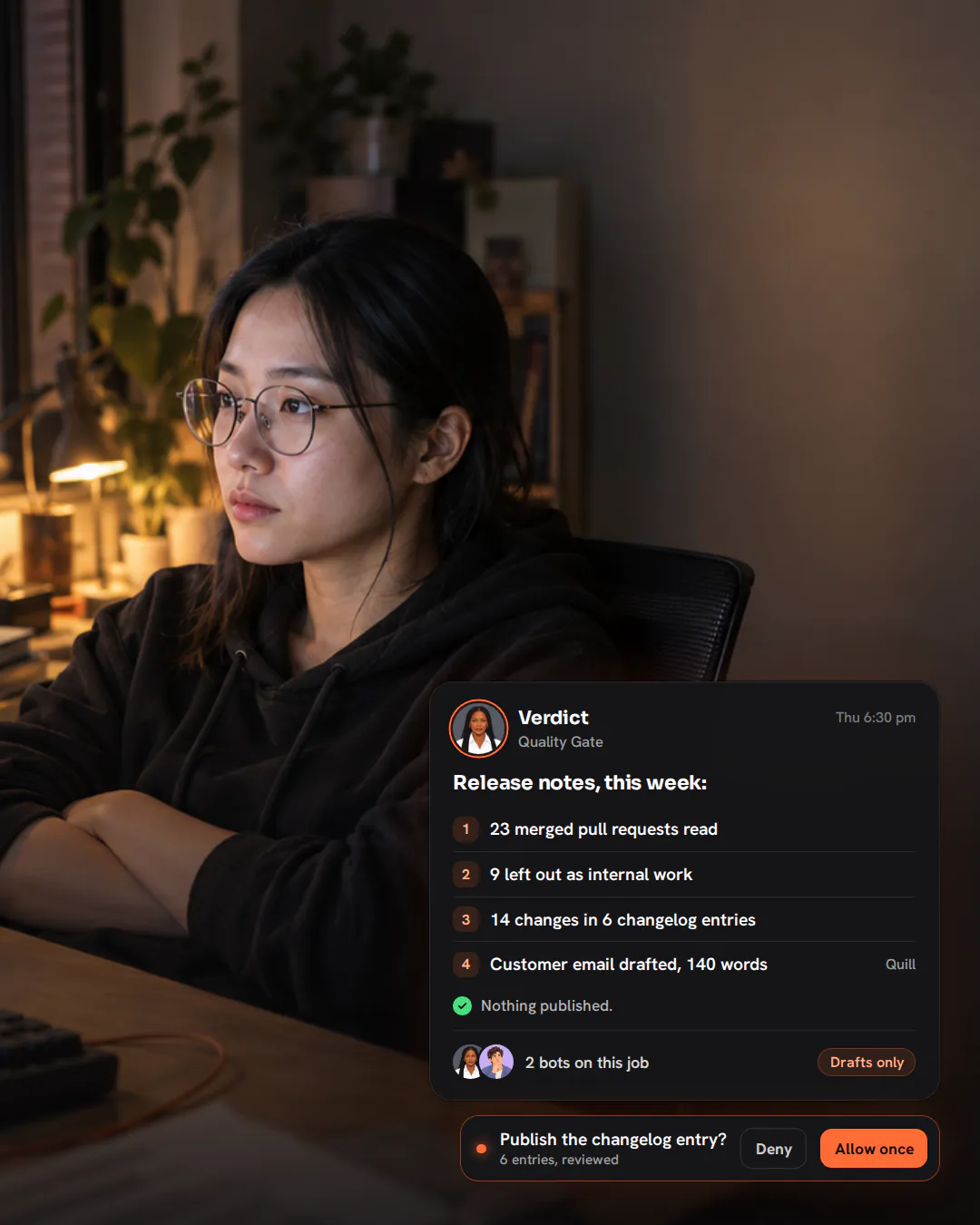An engineering lead leaning back with arms crossed at her desk on a Thursday evening, reviewing a monitor.